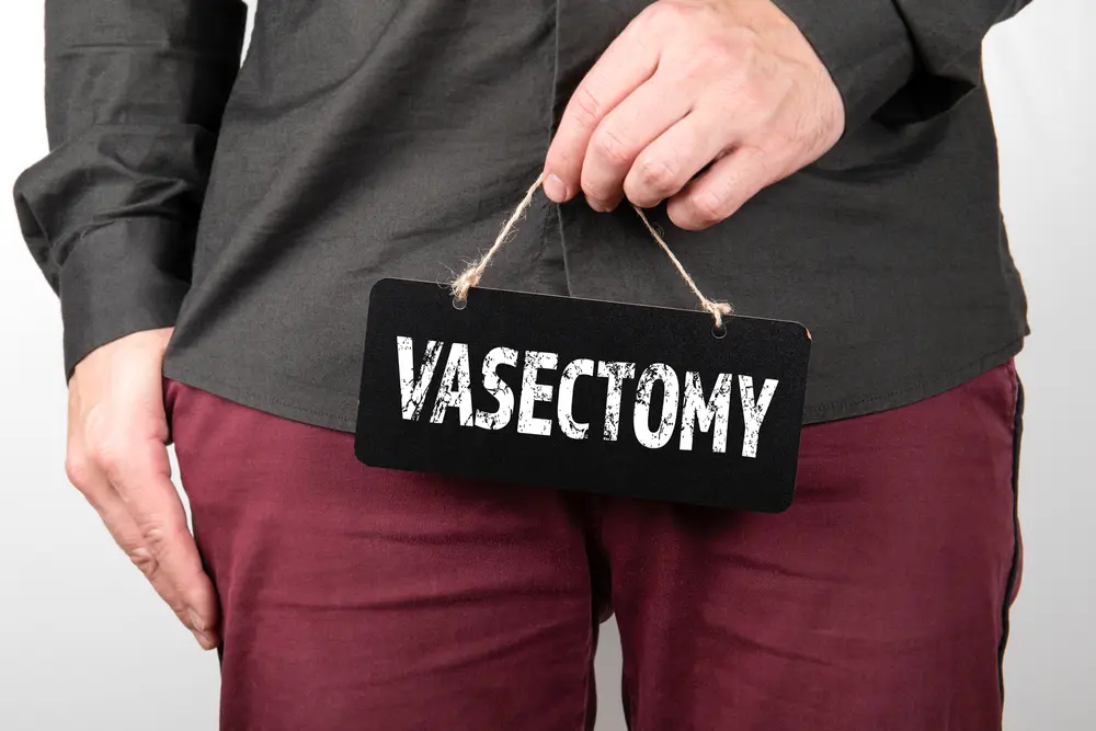 guy holding board that says vasectomy.